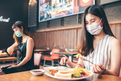 Young woman sitting on table at restaurant