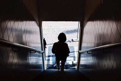Rear view of man standing on staircase