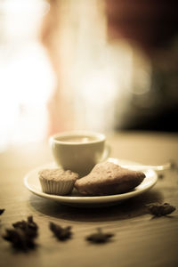 Close-up of coffee cup with cupcake on table