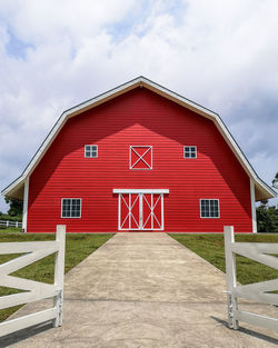 Red house on footpath against sky