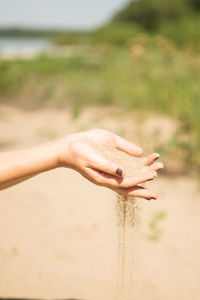 Midsection of woman hand on sand at beach