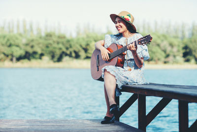 Man sitting on guitar against lake