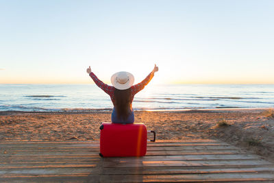 Rear view of person at beach against sky during sunset