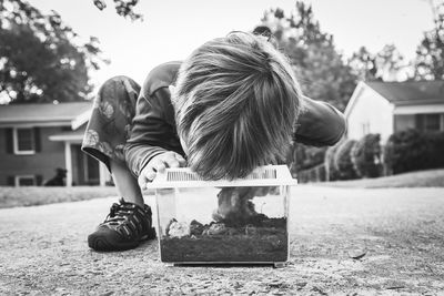 Child looking at frog in terrarium outdoors