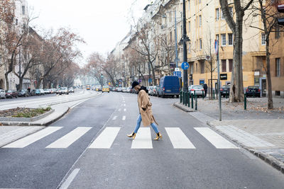 Rear view of woman walking on road in city