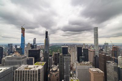 Aerial view of buildings in city against cloudy sky