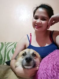 Portrait of teenage girl with dog at home