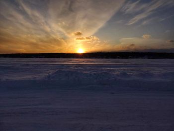 Scenic view of snow covered land during sunset