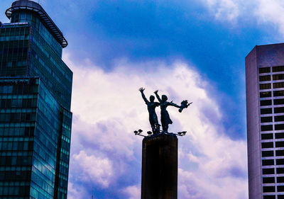 Low angle view of statue against building against sky