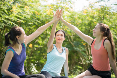 Yoga instructor giving high-five to women at park