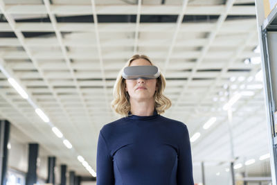 Businesswoman with virtual reality simulator at warehouse