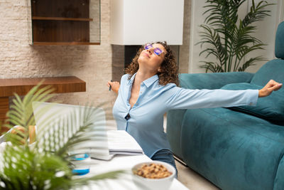 Young woman using mobile phone while sitting on sofa at home