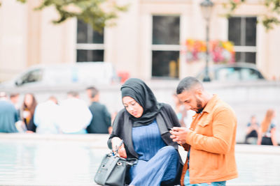 Young woman using mobile phone in front of building