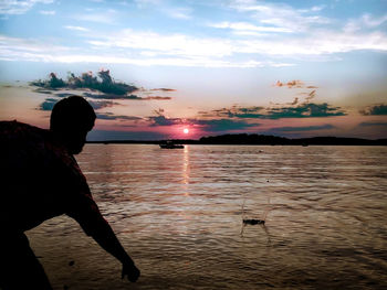 Woman looking at sea against sky during sunset