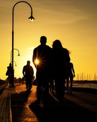 Rear view of silhouette people on street at sunset