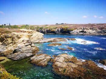 Rocks on shore against blue sky