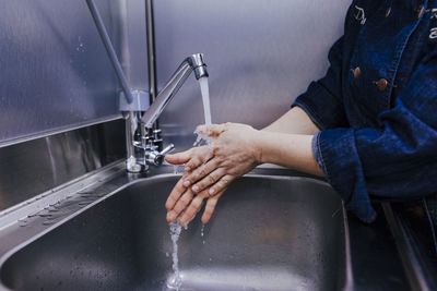 Midsection of woman washing hands in sink