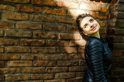 Portrait of smiling girl standing against brick wall