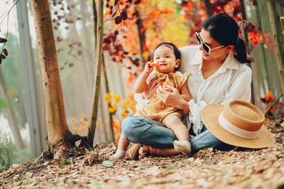 Rear view of mother and daughter sitting outdoors