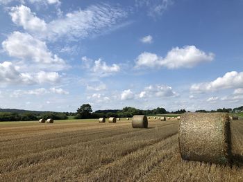 Hay bales on field against sky