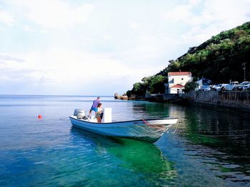 People on boat in sea against sky