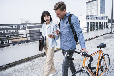 Male and female friends talking over mobile phone in city