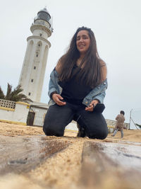 Portrait of smiling young woman sitting against sky