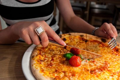 Midsection of woman having pizza at table