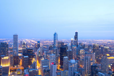 Illuminated cityscape against blue sky