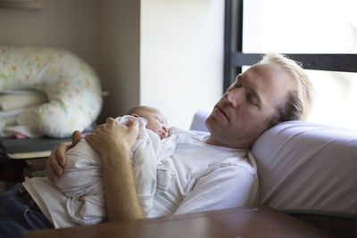 Father with newborn daughter sleeping at home