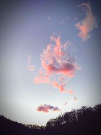 Low angle view of trees against cloudy sky