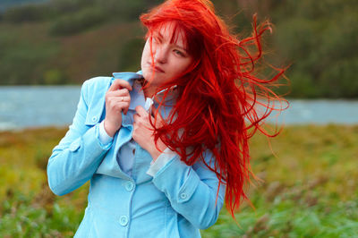 Young woman with redhead holding jacket at lakeshore