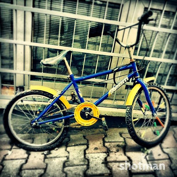 bicycle, mode of transport, transportation, land vehicle, stationary, building exterior, parking, parked, architecture, leaning, built structure, wall - building feature, cycle, day, blue, street, outdoors, side view, wheel, no people