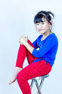 Portrait of cute girl sitting against white background
