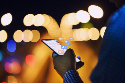 Midsection of man holding mobile phone at night