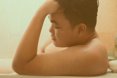 Close-up portrait of shirtless young man sitting on floor