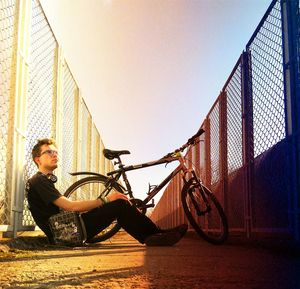 Man sitting on bicycle against sky