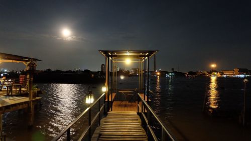 View of pier over calm river at night