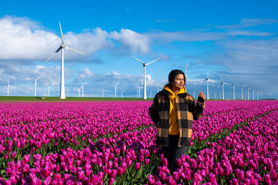 Rear view of woman standing on field against sky