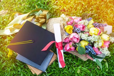 High angle view of mortarboard with flowers on grass