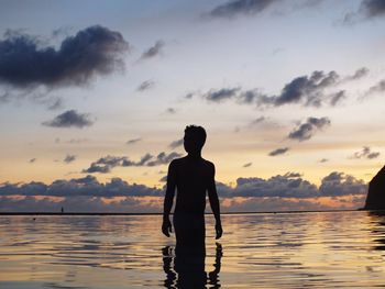 Silhouette man looking at sea against sky