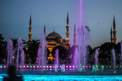 Mosque with purple fountain water as a postcard in sunset with minarets and blue sky