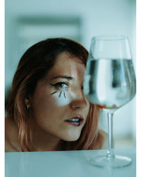 Close-up portrait of a serious young woman drinking glass