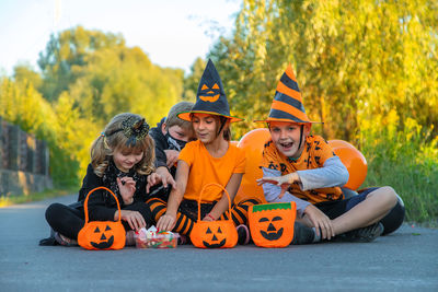 Cute kids sitting on road wearing halloween costume