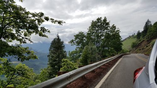 Cars on road against cloudy sky