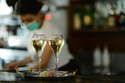 Female bartender wearing face mask prepare sparkling white wine