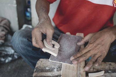 Midsection of man making number 5 of wood