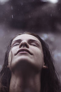 Close-up of teenage girl looking up during rainy season