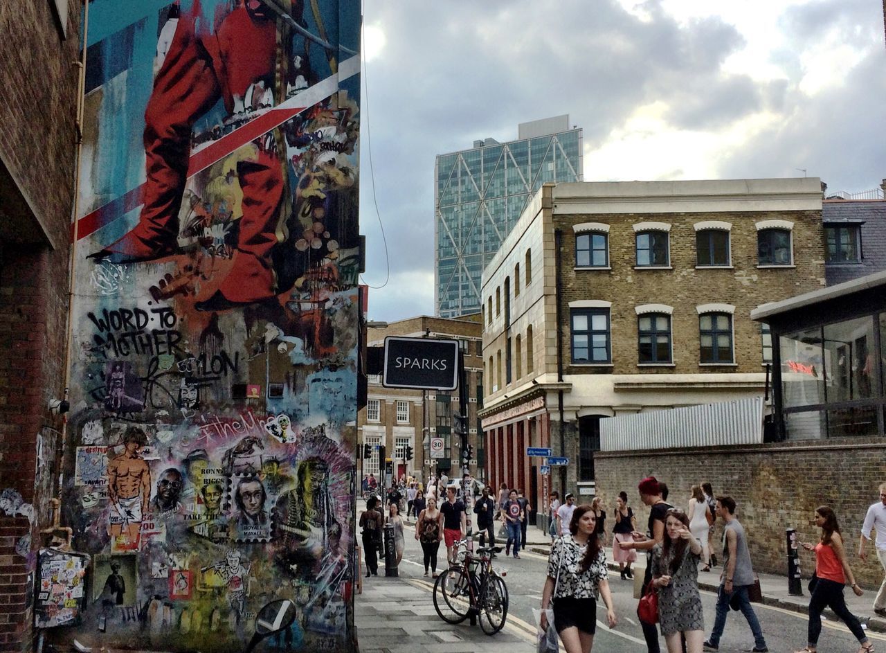 architecture, building exterior, built structure, large group of people, city, men, street, person, city life, graffiti, lifestyles, building, text, walking, sky, leisure activity, day, western script, outdoors