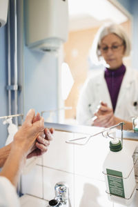 Cropped image of senior female doctor washing hands in hospital bathroom